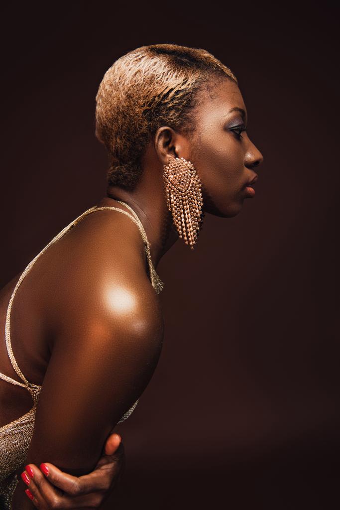 Seitenansicht der attraktiven afrikanisch-amerikanischen Frau mit kurzen Haaren isoliert auf braun - Foto, Bild