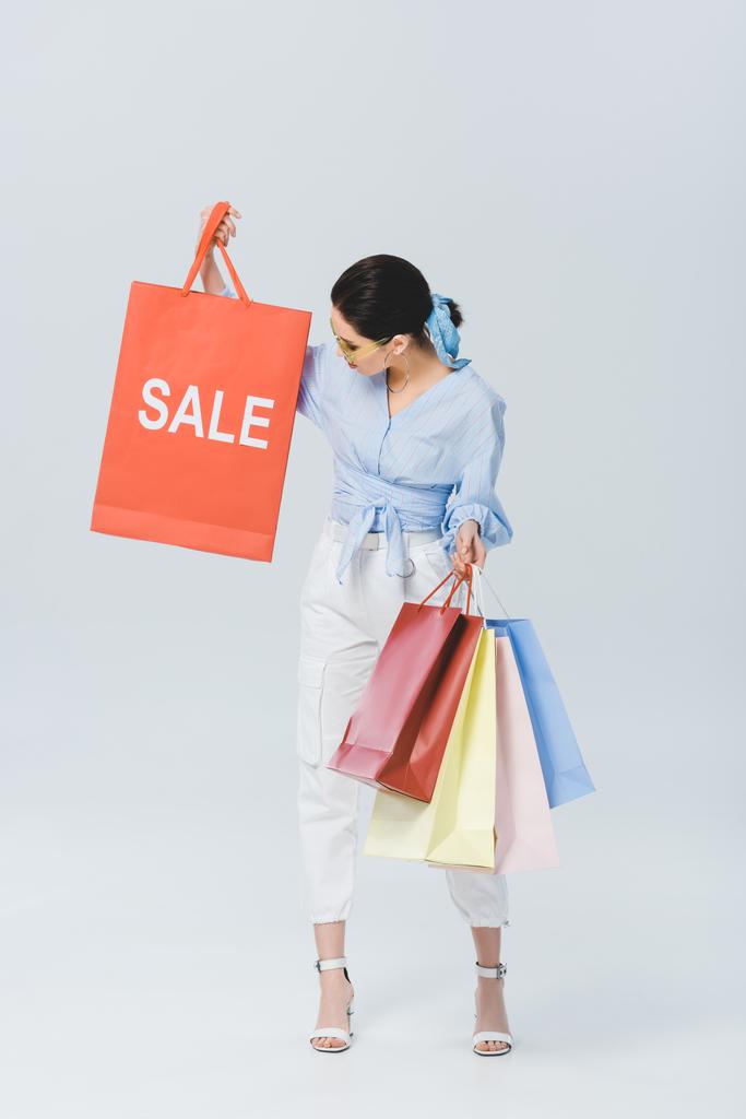 krásná stylová dívka držící nákupní tašku s prodejními slovy na šedé - Fotografie, Obrázek