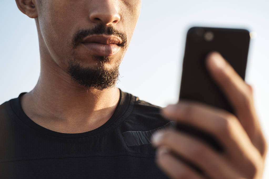 Yakışıklı genç Afrika güçlü spor adam cep telefonu kullanarak açık havada. - Fotoğraf, Görsel