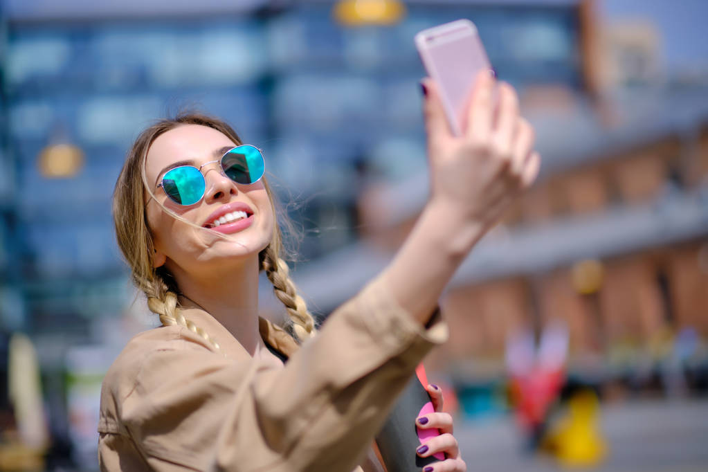 Selfie van de jonge vrouw in de straat met een smartphone.  - Foto, afbeelding