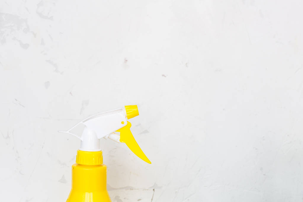 einfache gelbe Kunststoff-Handsprühflasche auf grauem Hintergrund. - Foto, Bild