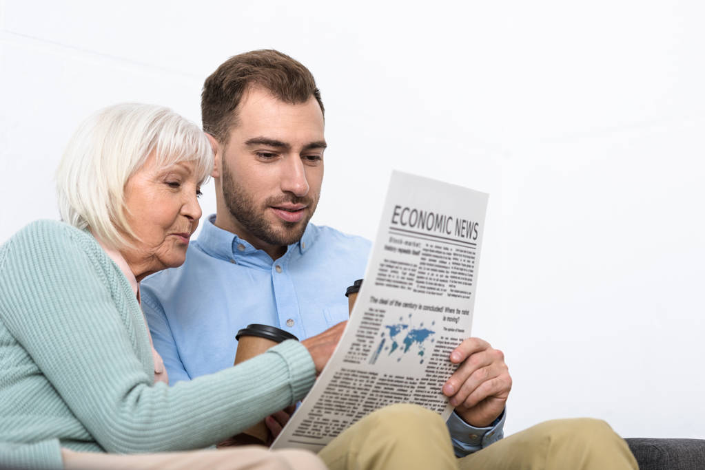 man en senior moeder lezen krant thuis - Foto, afbeelding