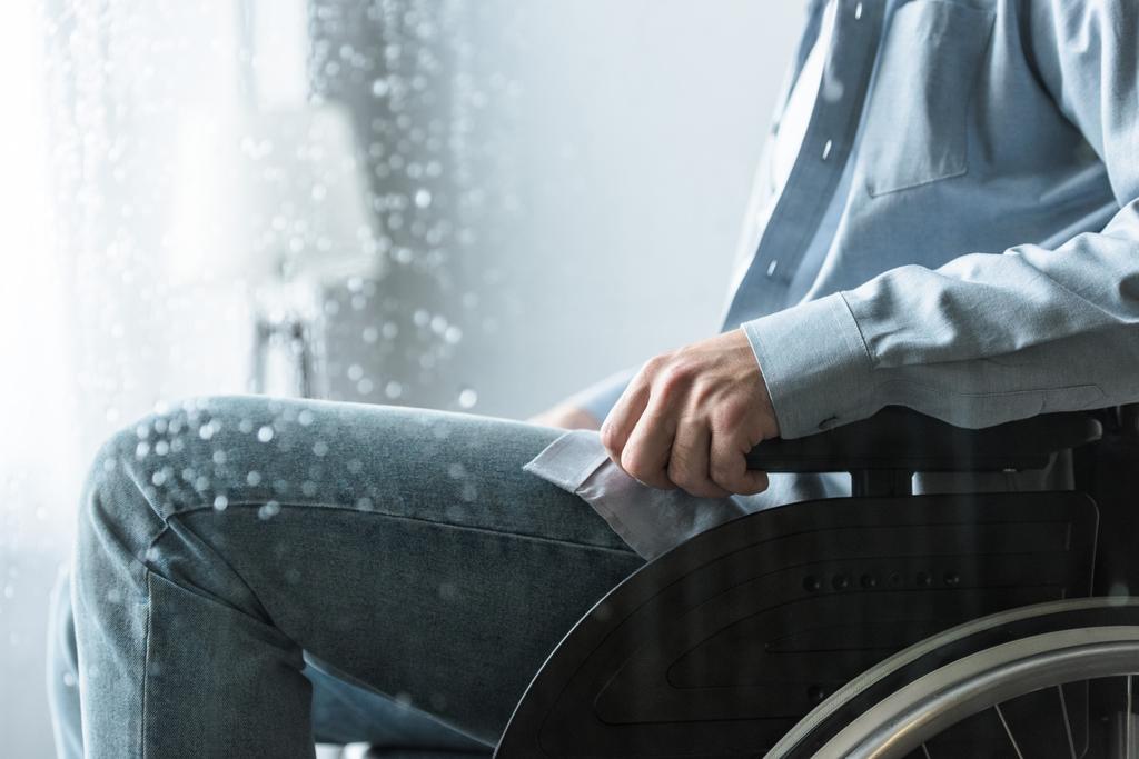 Vammaisen miehen osittainen näkymä pyörätuolissa olevissa farkuissa
 - Valokuva, kuva