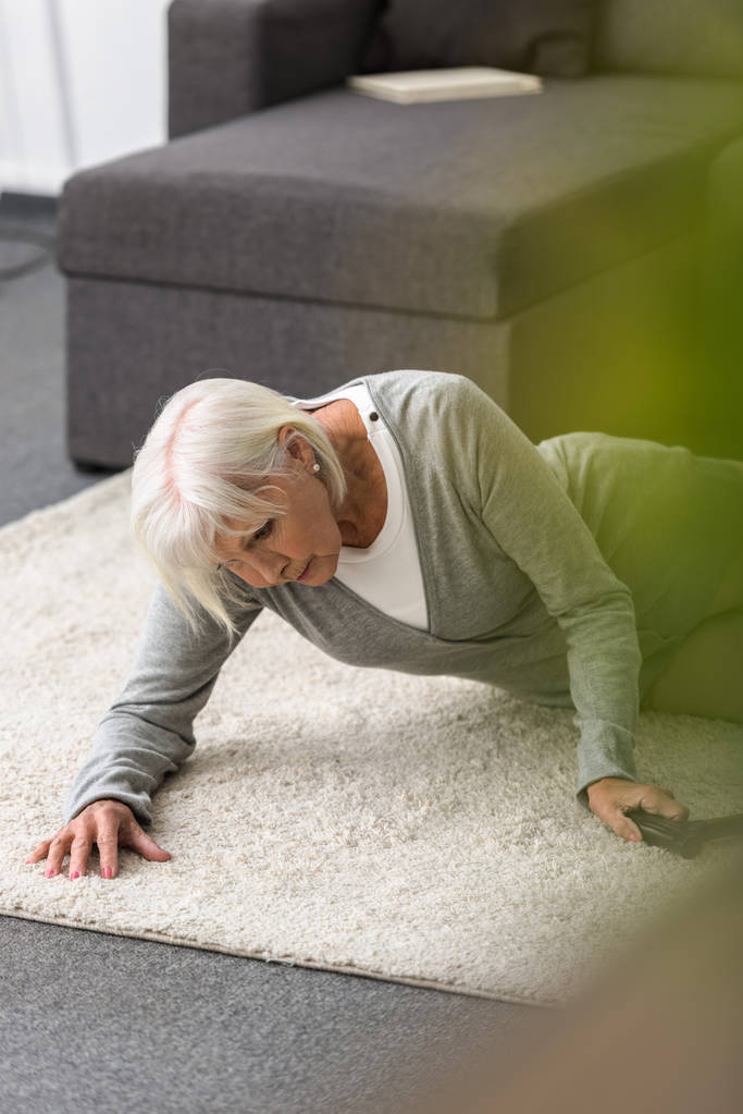 Kranke Seniorin mit Stock auf Teppich liegend - Foto, Bild
