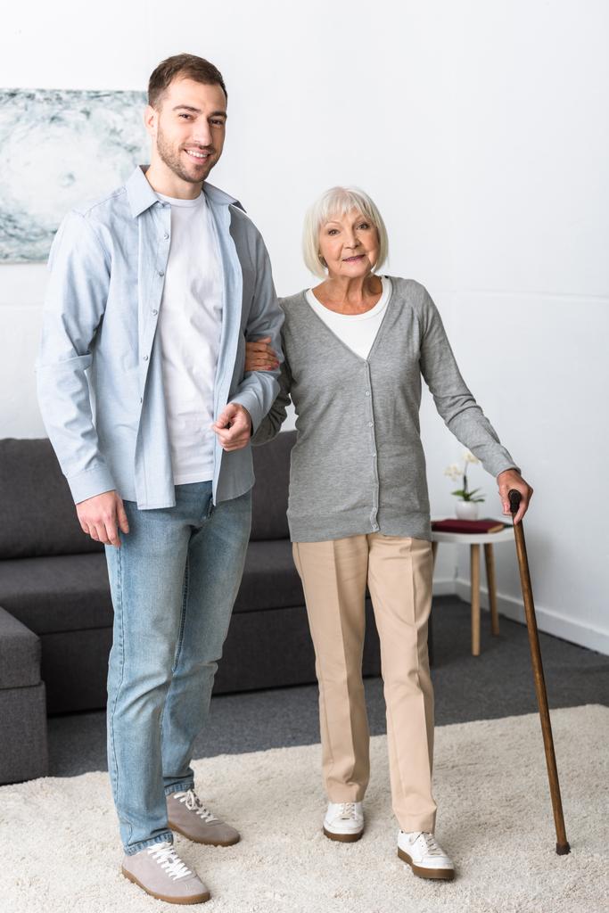pełny widok długości człowieka pomagając starszy matka z trzciny w domu - Zdjęcie, obraz