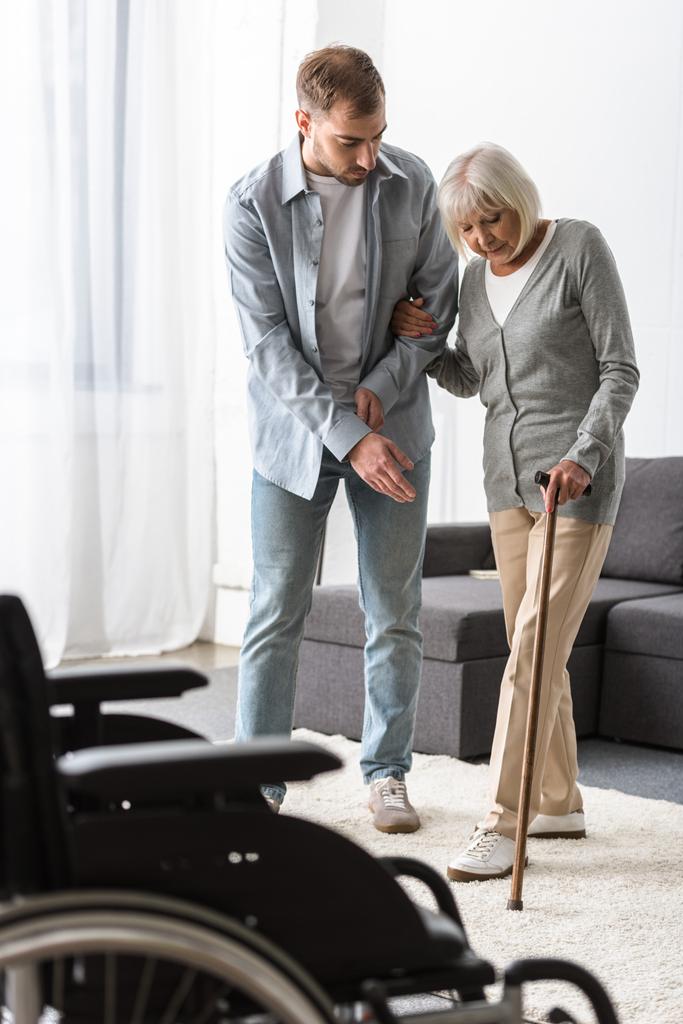Mann hilft Seniorin zu Hause mit Rohrstock - Foto, Bild