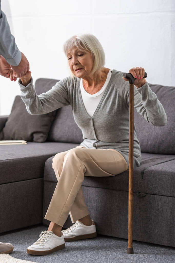 Mann hilft Seniorin im Wohnzimmer - Foto, Bild
