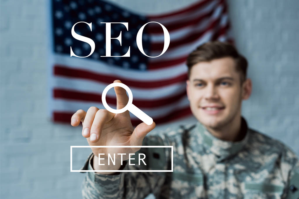 selective focus of happy man in military uniform pointing with finger at seo lettering  - Photo, Image
