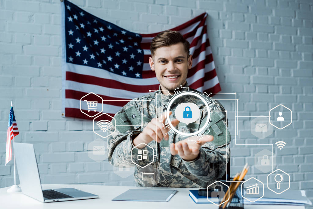 šťastný muž v vojenské uniformě ukazující prstem na virtuálním visacím zámku blízko laptopu  - Fotografie, Obrázek
