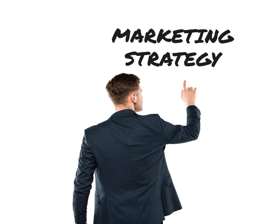vista posterior del hombre señalando con el dedo las letras de estrategia de marketing en blanco
  - Foto, Imagen