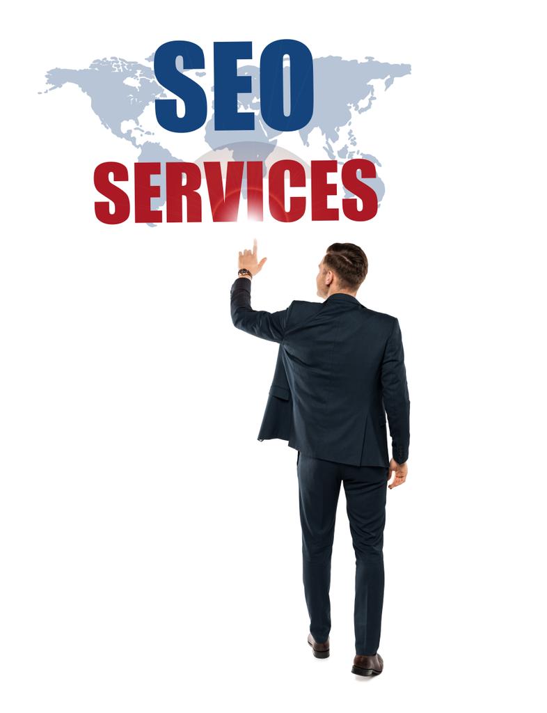 back view of man pointing with finger at seo services lettering while standing isolated on white  - Photo, Image