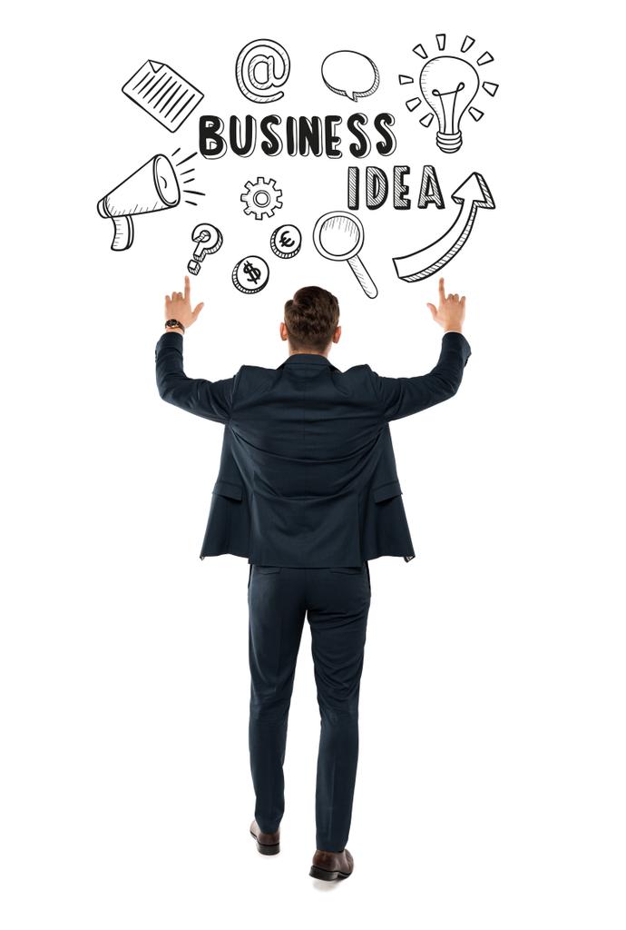 back view of man pointing with fingers at business idea lettering while standing isolated on white  - Photo, Image