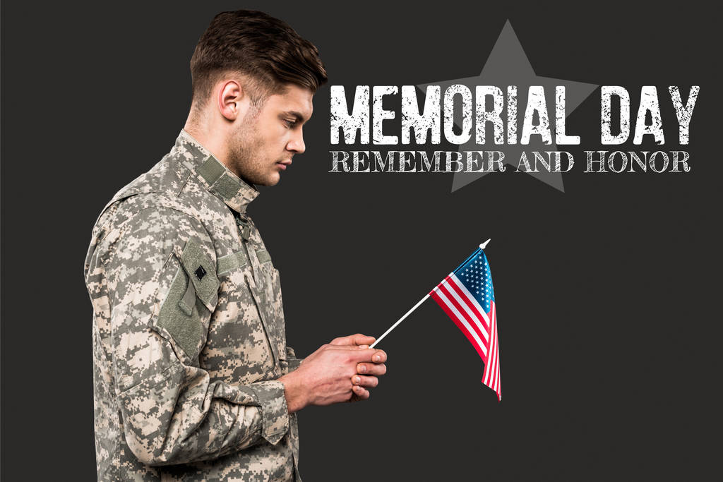 λυπημένος άνθρωπος με στρατιωτική στολή κρατώντας αμερικάνικη σημαία κοντά στο μνημόσυνο γράμματα σε γκρι  - Φωτογραφία, εικόνα