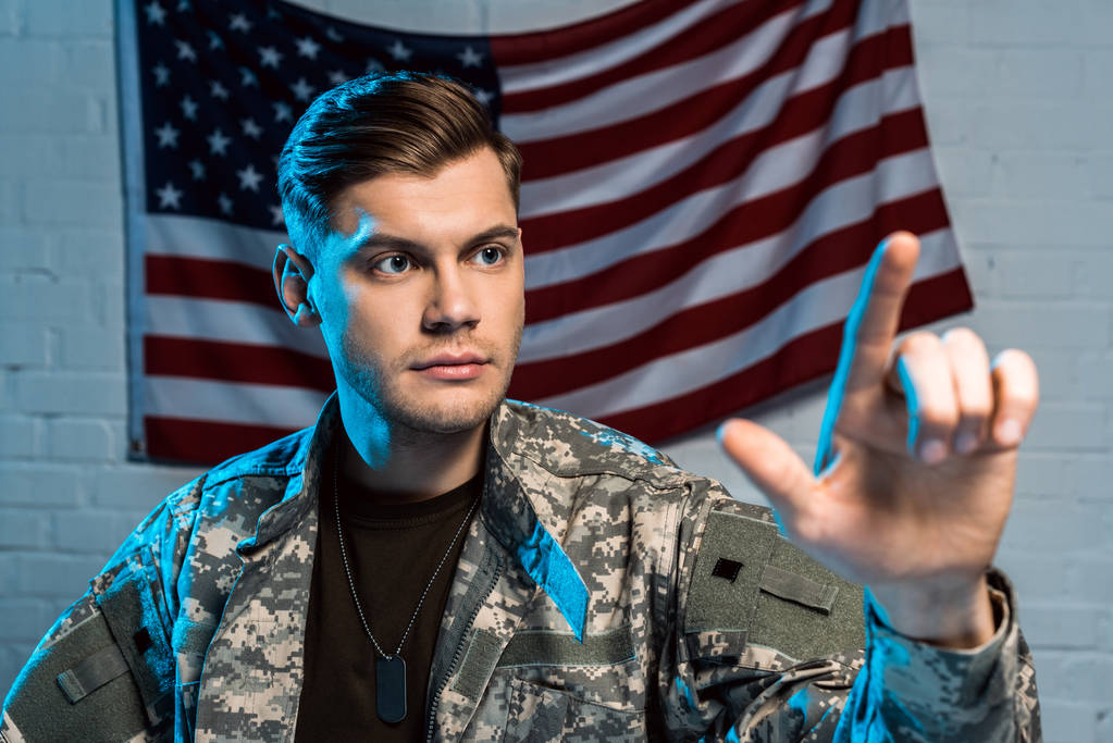 foyer sélectif du beau soldat pointant avec le doigt près du drapeau américain
  - Photo, image