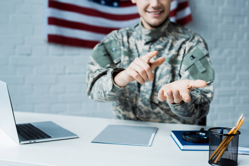 vista cortada de homem feliz em uniforme militar apontando com o dedo no escritório
 - Foto, Imagem