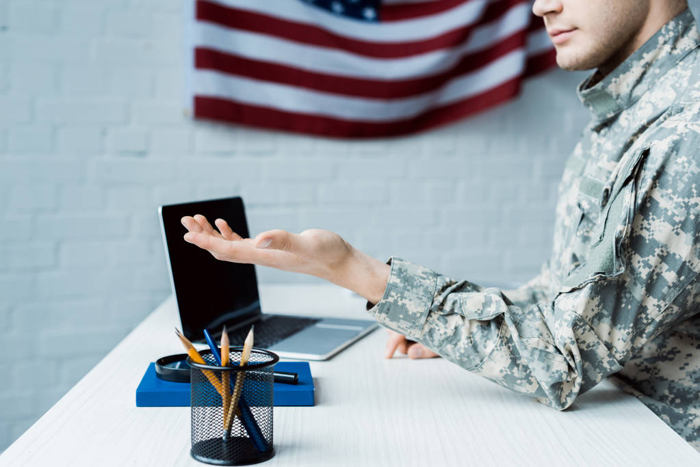 vista recortada de soldado gesto cerca de la computadora portátil con pantalla en blanco
  - Foto, imagen