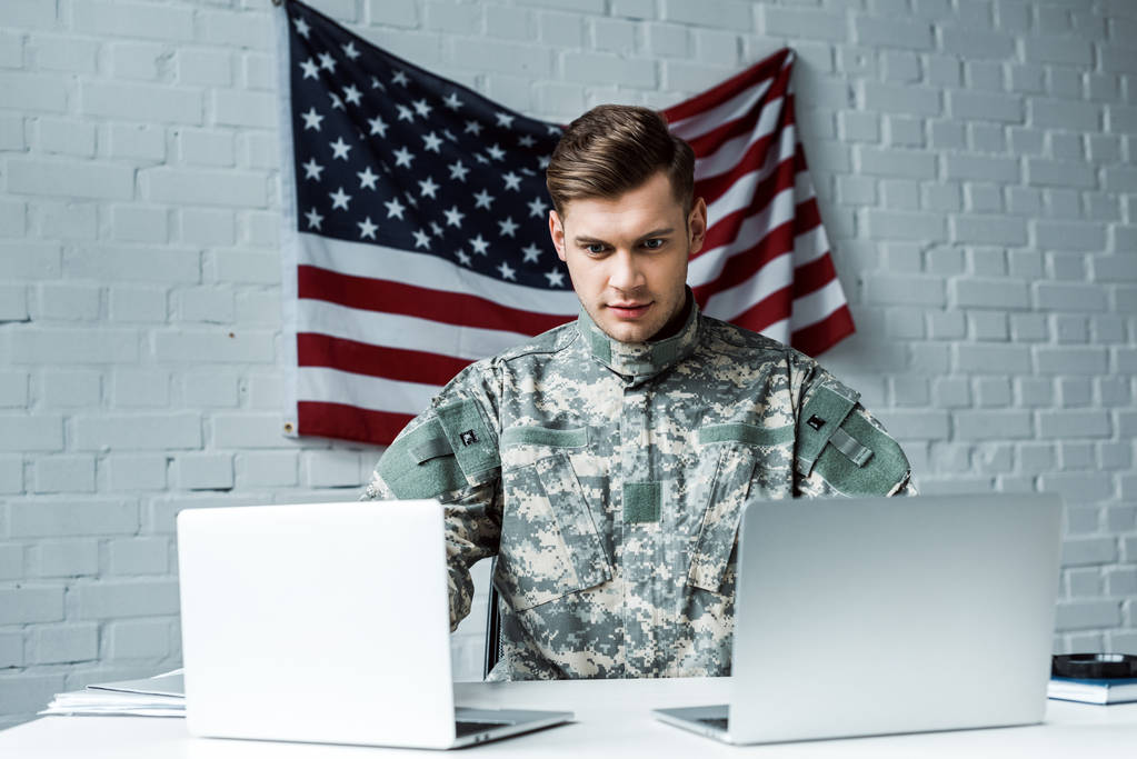 bell'uomo in uniforme militare con i computer portatili in ufficio
  - Foto, immagini