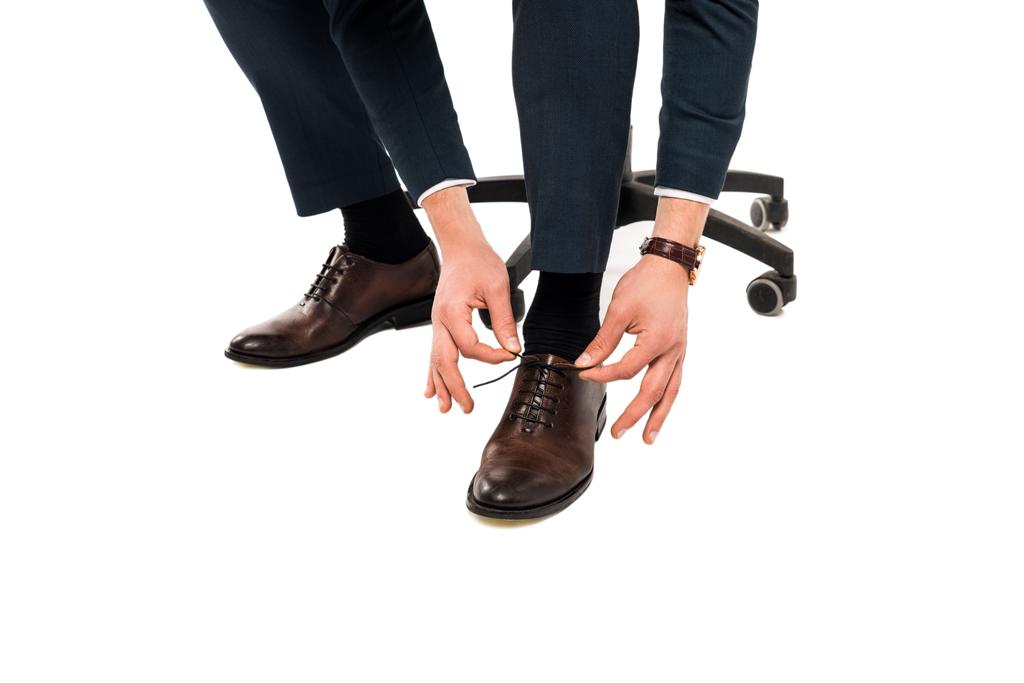 白で隔離された靴ひもを結ぶビジネスマンのトリミングされたビュー   - 写真・画像