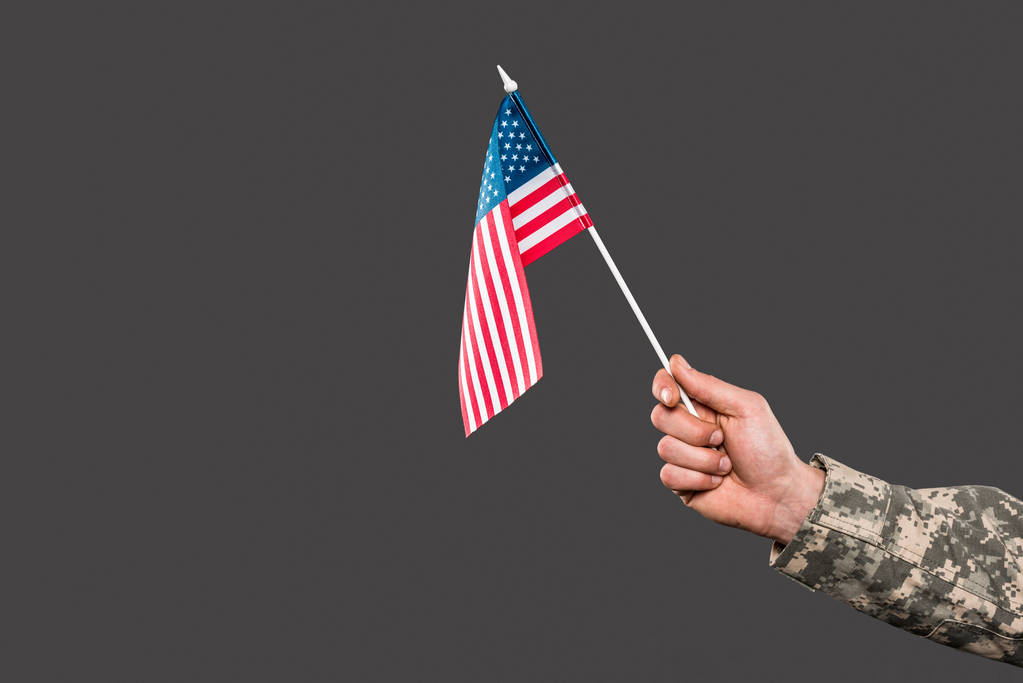 περικομμένη όψη του στρατιώτη που κρατά τη σημαία της Αμερικής απομονωμένη σε γκρι  - Φωτογραφία, εικόνα