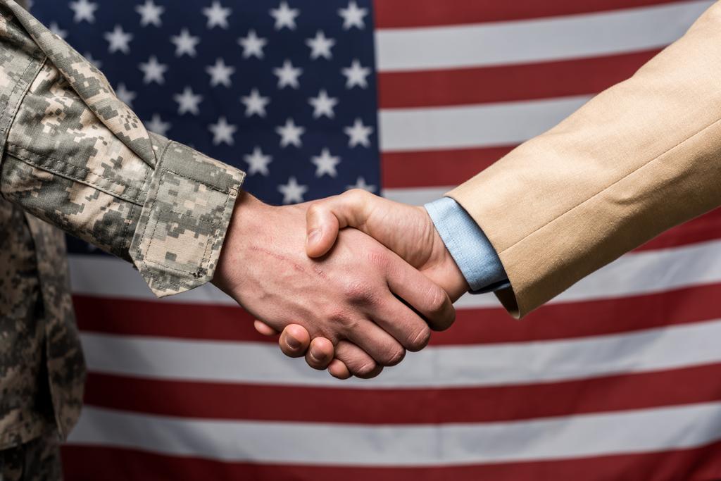 selektywne skupić wojskowych mężczyzn drżenie rąk w pobliżu amerykańskiej flagi  - Zdjęcie, obraz