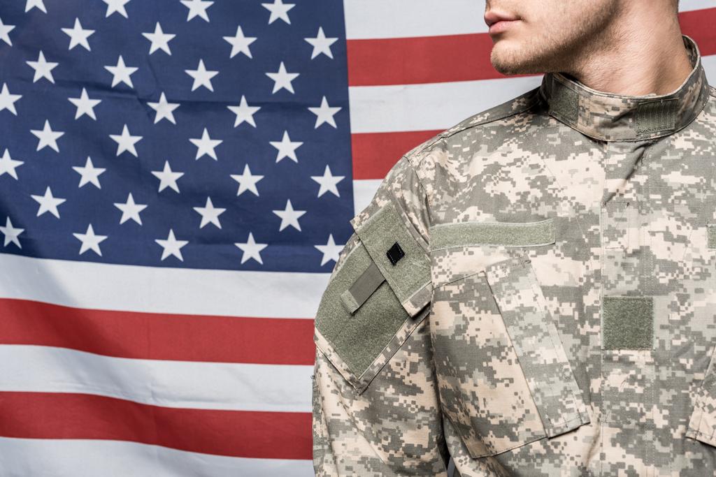 περικομμένη όψη του ανθρώπου με στρατιωτική ομοιόμορφη κοντά στη σημαία της Αμερικής - Φωτογραφία, εικόνα