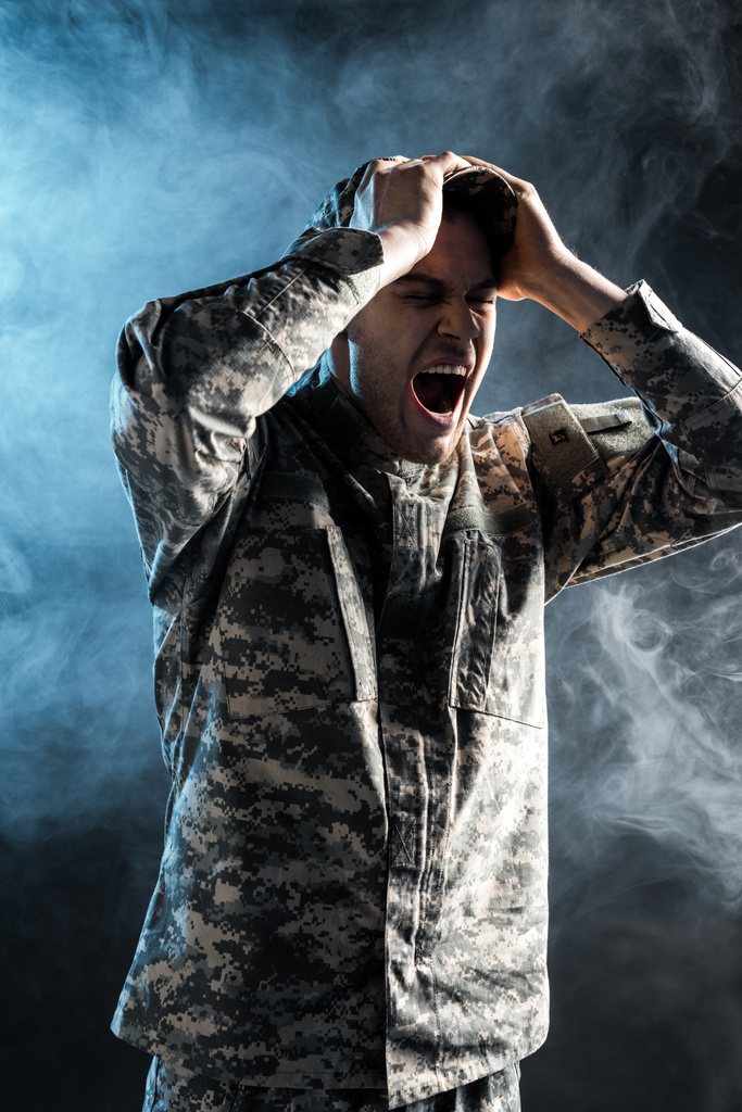 συναισθηματικός στρατιώτης με στρατιωτική στολή ουρλιάζοντας σε μαύρο με καπνό  - Φωτογραφία, εικόνα