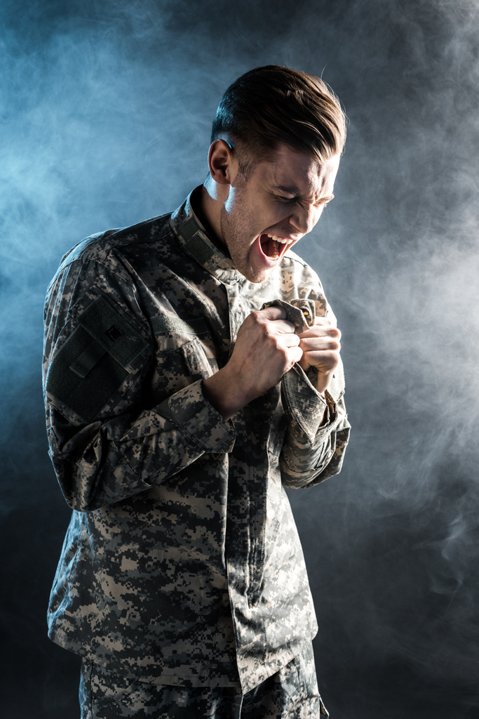 homem emocional em uniforme militar gritando em preto com fumaça
  - Foto, Imagem