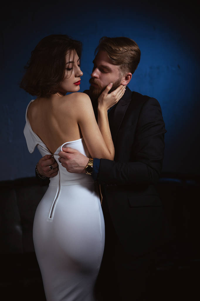 a man in a fit of passion unbuttons the dress of a young woman who embraces him - Photo, Image