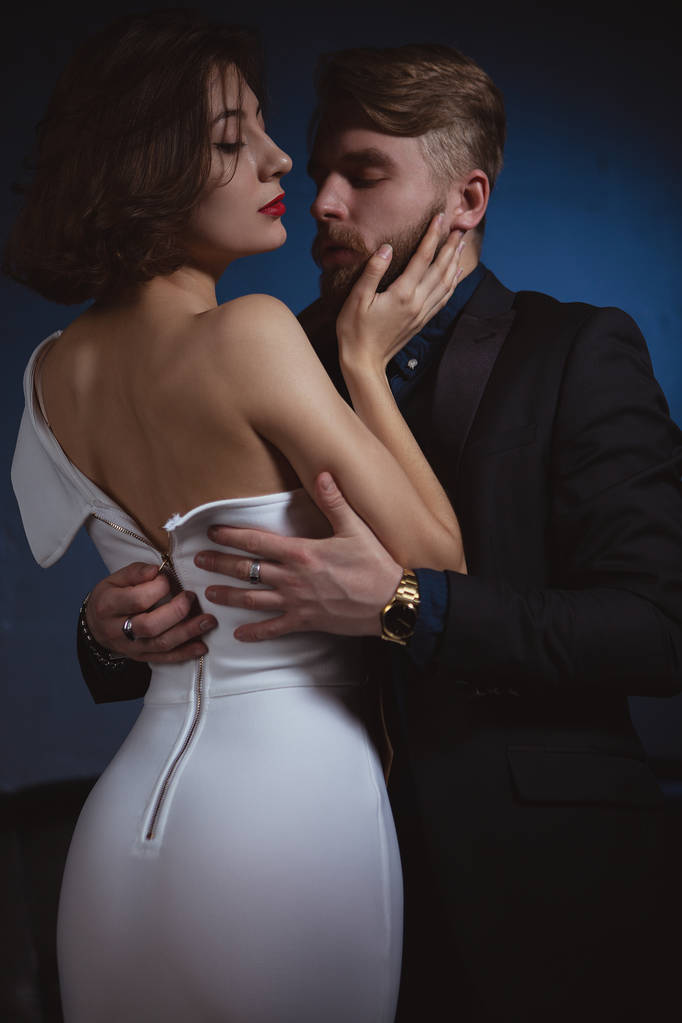 egy férfi illeszkedik a szenvedély unbuttons a ruha egy fiatal nő, aki magában foglalja őt - Fotó, kép