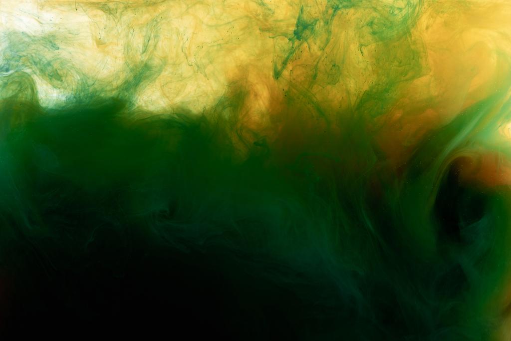 Close up view of dark green and orange paint mixing in water  - Photo, Image