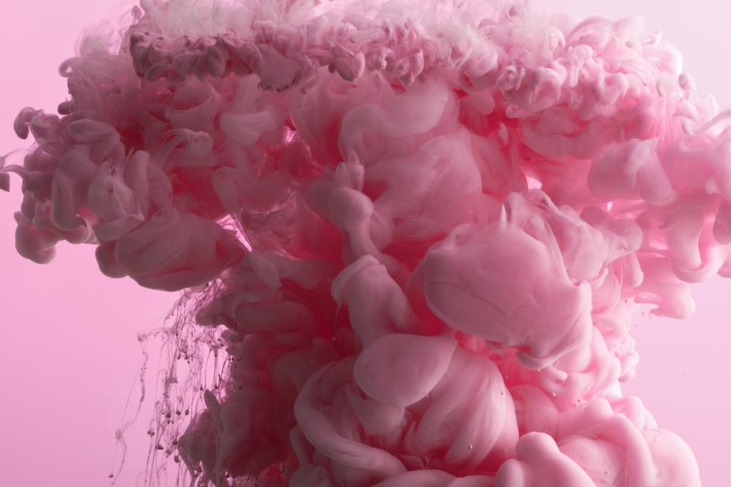 Vue rapprochée des éclaboussures de peinture rose dans l'eau isolée sur rose
 - Photo, image