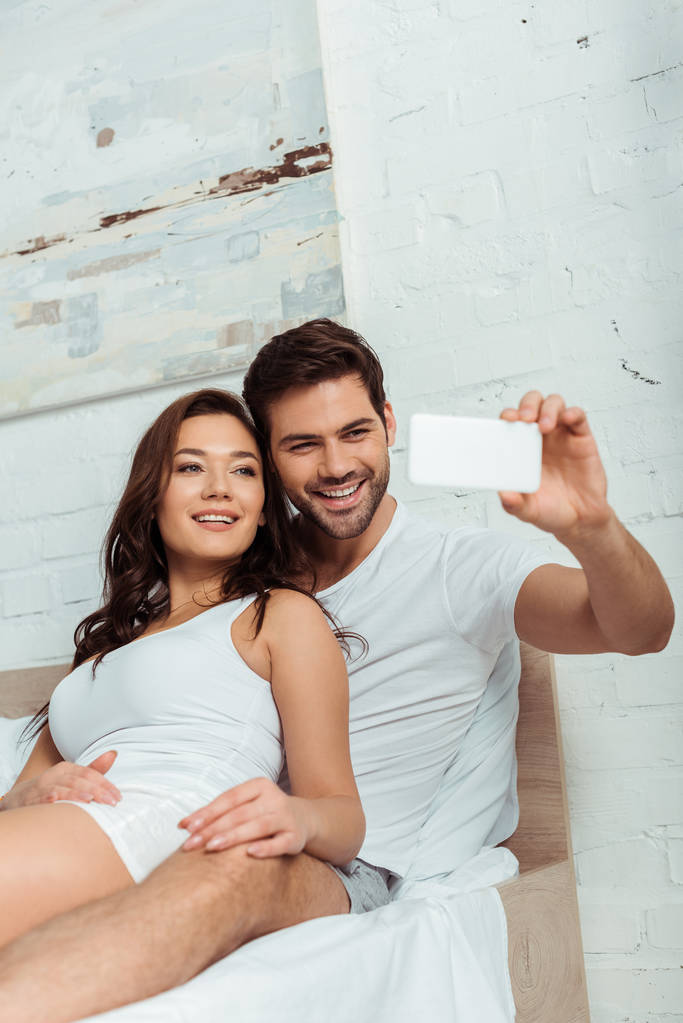 homme heureux souriant près de petite amie attrayante tout en prenant selfie
  - Photo, image