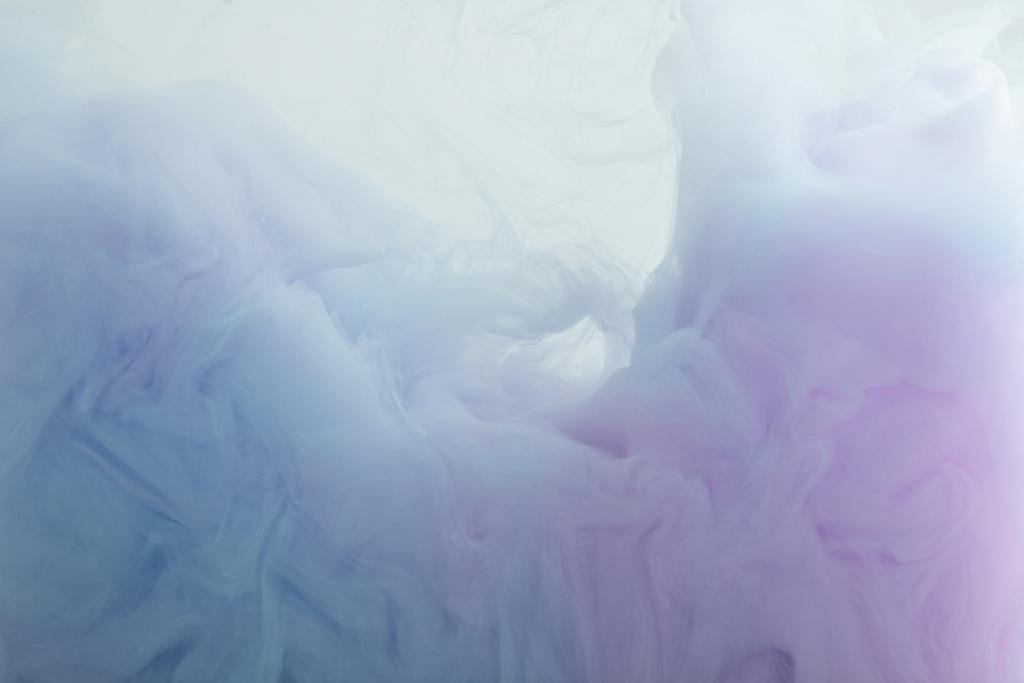 Close-up van licht blauwe en paarse verf dwarrelt in het water - Foto, afbeelding