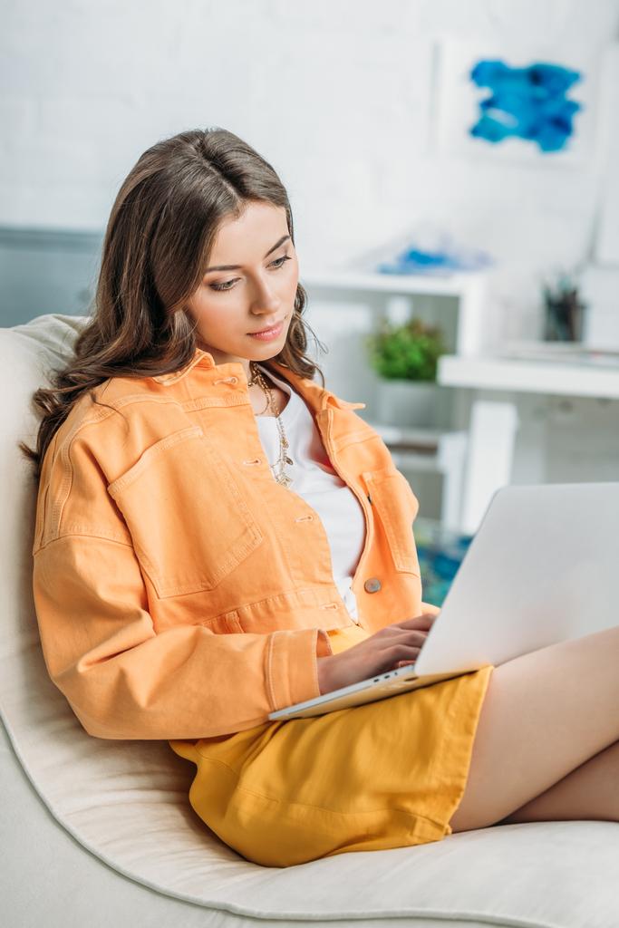 evde dizüstü bilgisayar kullanarak turuncu kapanış düşünceli genç kadın - Fotoğraf, Görsel