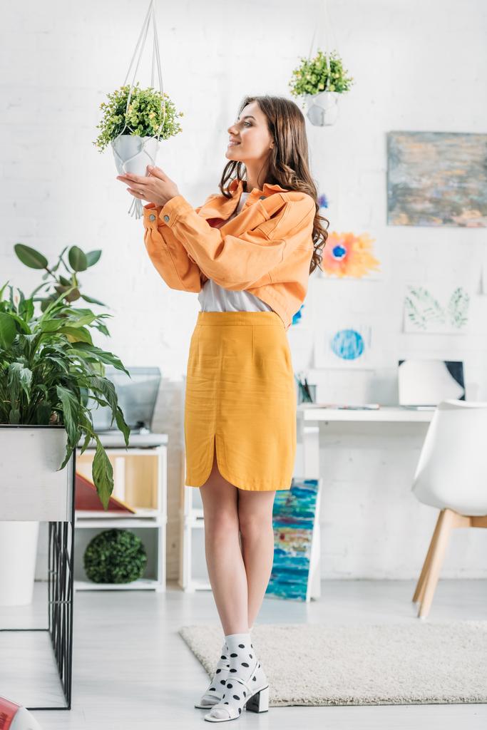 yeşil bitki ile saksı dokunmadan turuncu giyim trendy kadın - Fotoğraf, Görsel