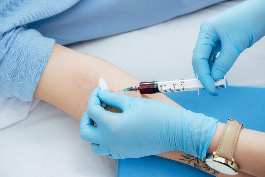 cropped view of donor and doctor with syringe obtaining blood sample - Photo, Image