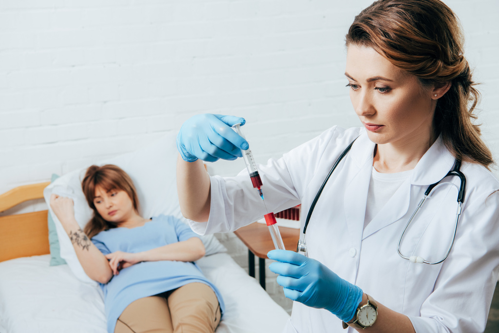 doador na cama e médico segurando seringa com amostra de sangue e tubo de ensaio
 - Foto, Imagem