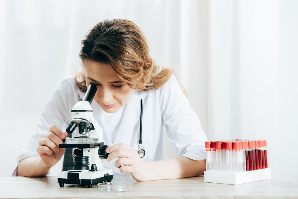 doctor en bata blanca usando microscopio en la clínica
 - Foto, Imagen