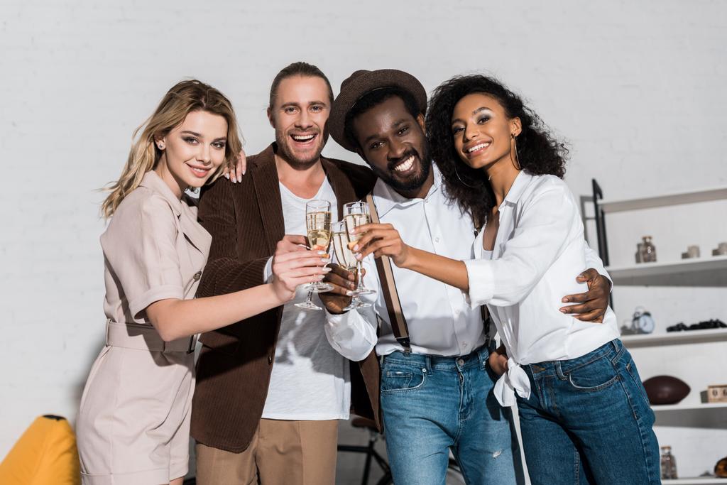 vista a basso angolo di allegri amici multiculturali sorridenti mentre tintinnano bicchieri di champagne
  - Foto, immagini