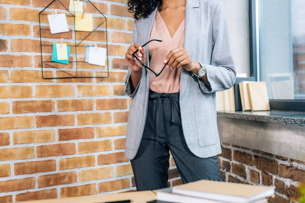 Cropped view of casual african american businesswoman holding glasses in loft office - Photo, Image