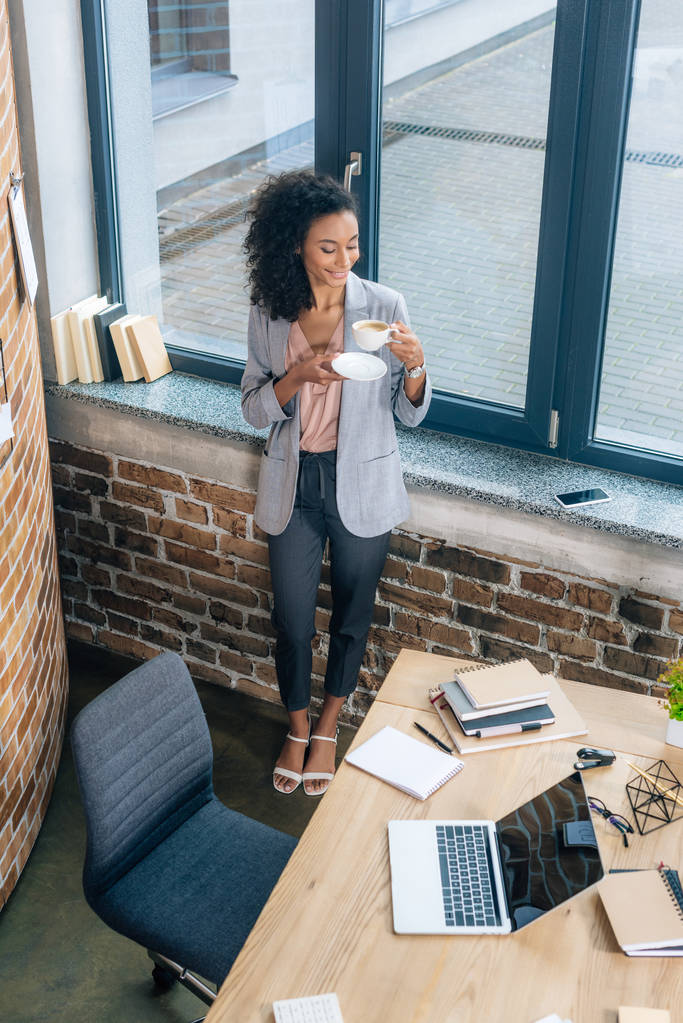 Високий кут Вид красивої афроамериканської бізнес-леді біля офісного столу з ноутбуком
 - Фото, зображення