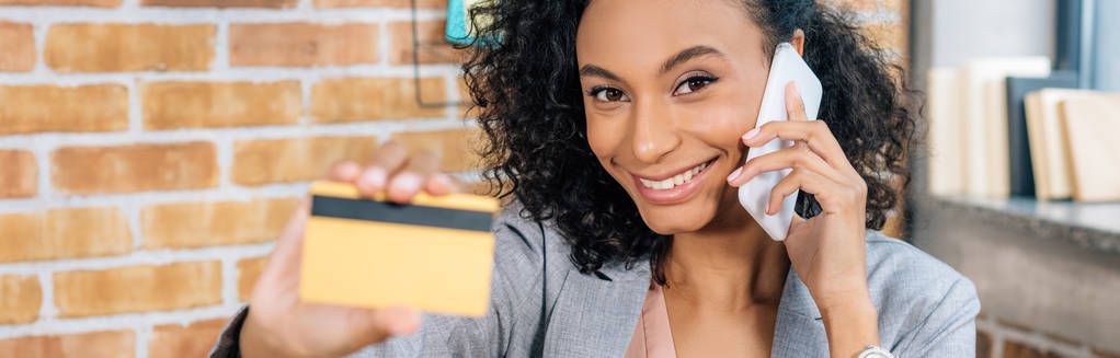plan panoramique de femme d'affaires afro-américaine occasionnelle avec carte de crédit parlant sur smartphone
 - Photo, image