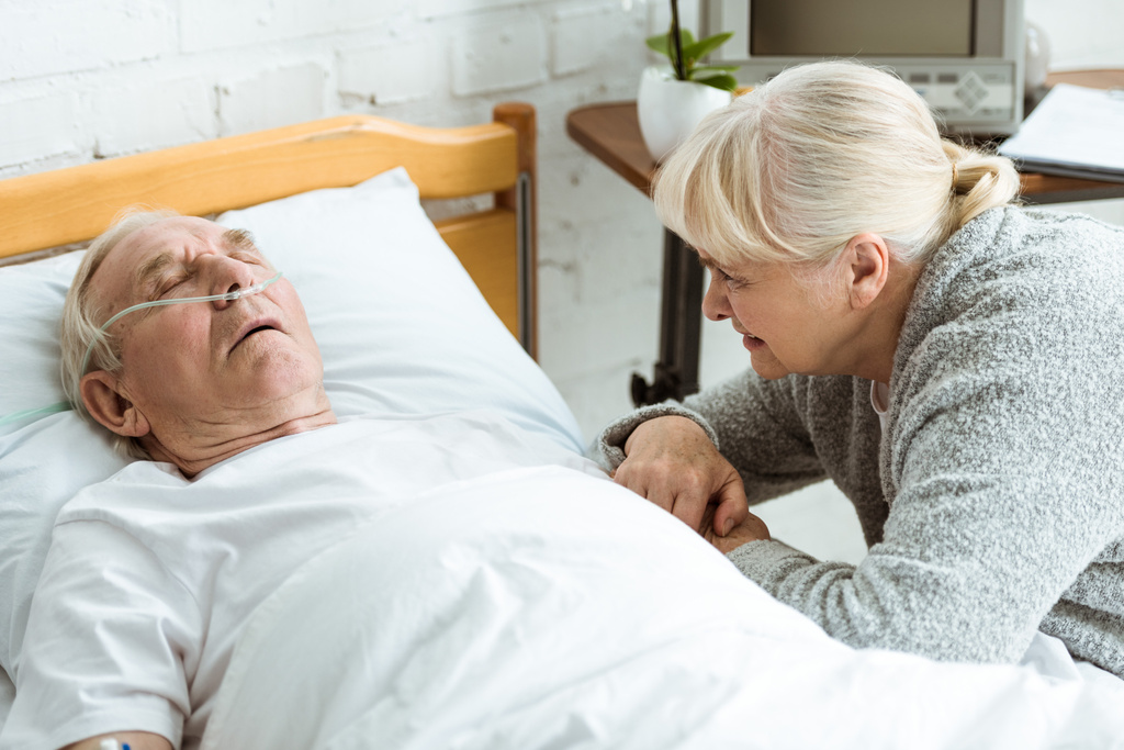 szomorú idős nő férjével kómában a kórházban - Fotó, kép