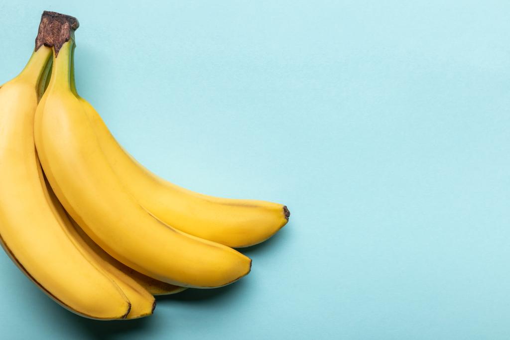 vista superior de plátanos amarillos maduros sobre fondo azul con espacio para copiar
 - Foto, imagen