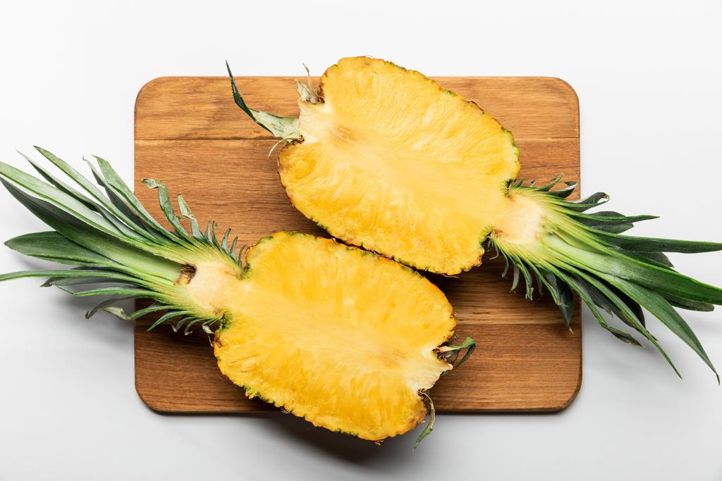 top view of cut ripe yellow pineapple on wooden chopping board on white background - Photo, Image
