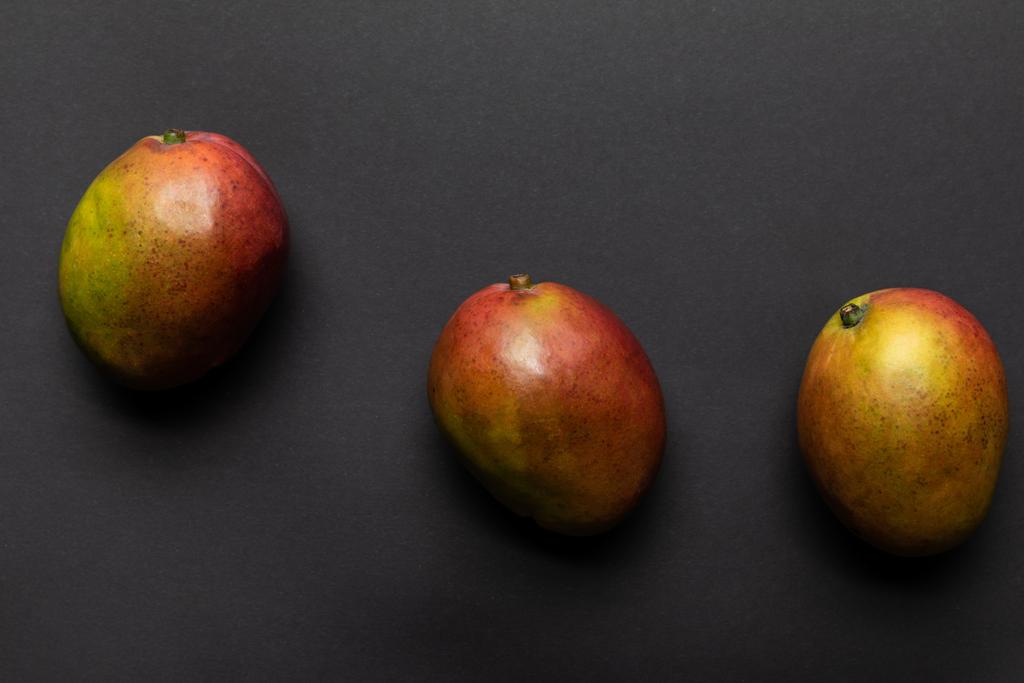 siyah arka plan üzerinde olgun tatlı bütün mango üst görünümü - Fotoğraf, Görsel