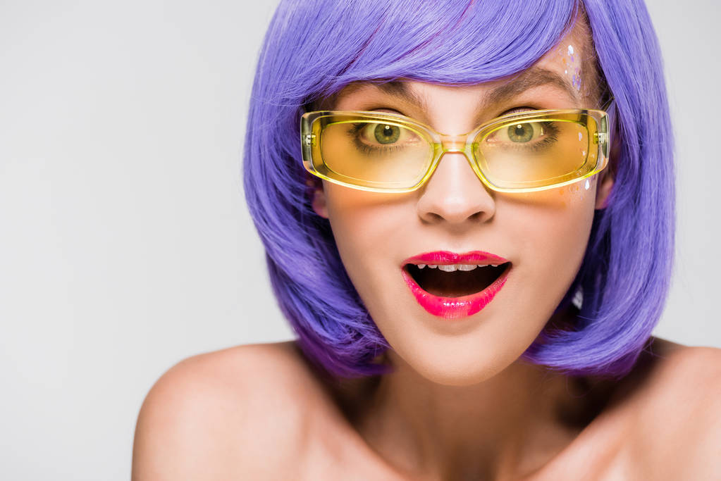chica excitada en peluca púrpura y gafas de sol de moda aisladas en gris
 - Foto, imagen