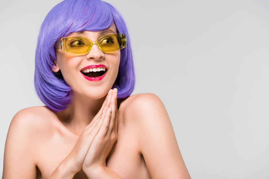 szép izgatott nő, lila paróka és napszemüveg izolált szürke - Fotó, kép