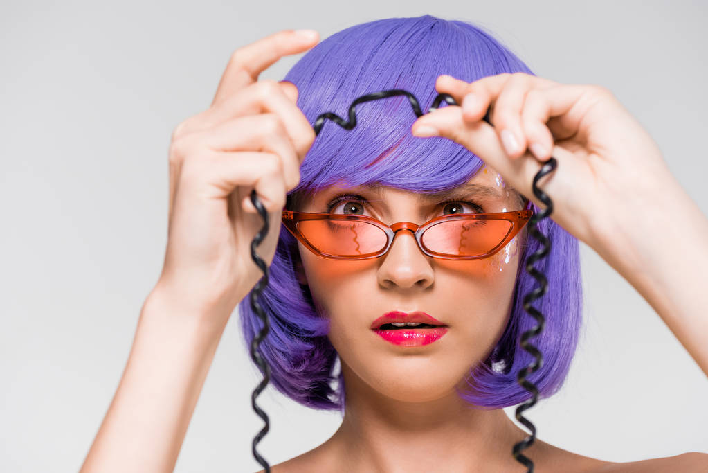woman in purple wig looking at cord of vintage telephone, isolated on grey - Photo, Image