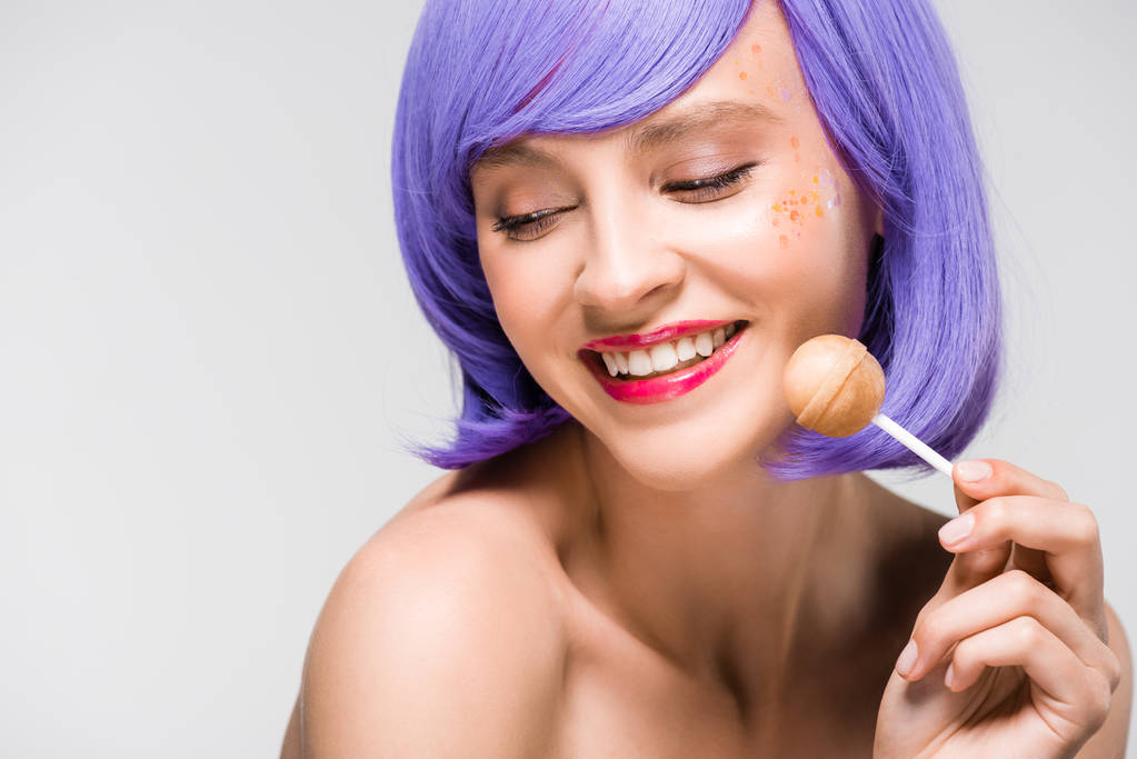 chica desnuda sonriente en peluca púrpura sosteniendo dulce piruleta, aislado en gris
 - Foto, Imagen